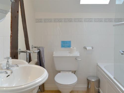 a white bathroom with a toilet and a sink at The Old Stables in Standon