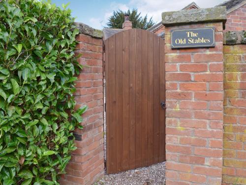 a wooden gate in a brick wall with a sign at The Old Stables in Standon