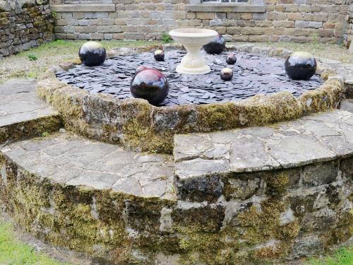 a garden with a vase and balls on the ground at Crossgates - 9562 in Grantley