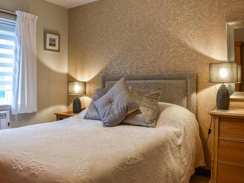 a bedroom with a bed with pillows on it at Riverbank Cottage in Pooley Bridge