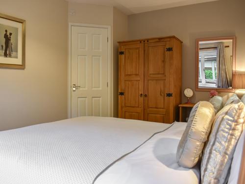 a bedroom with a white bed and a cabinet at Riverbank Cottage in Pooley Bridge