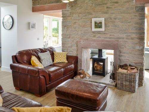 a living room with a leather couch and a fireplace at Greenford Farm in Newtyle