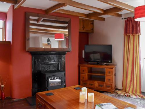 a living room with a fireplace and a television at Pineview Cottage in Downderry