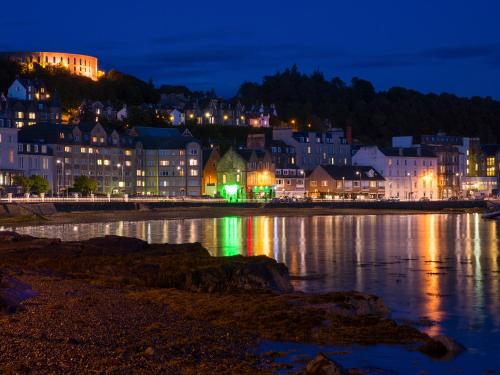 a city at night with lights on the water at Seaview Cottage in Ellanbeich