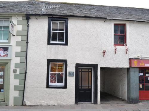 a white building with a black door on a street at Uncle's Cottage in Keswick