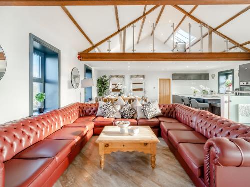 a living room with a red leather couch and a table at North Plain Barn in Bowness-on-Solway