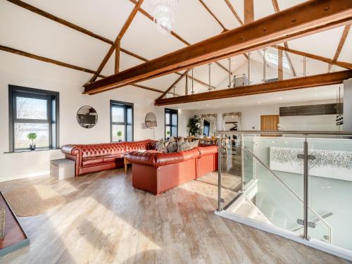 a large living room with red leather furniture and windows at North Plain Barn in Bowness-on-Solway