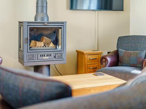 a living room with a fireplace with two chairs and a table at Limecroft in Malham