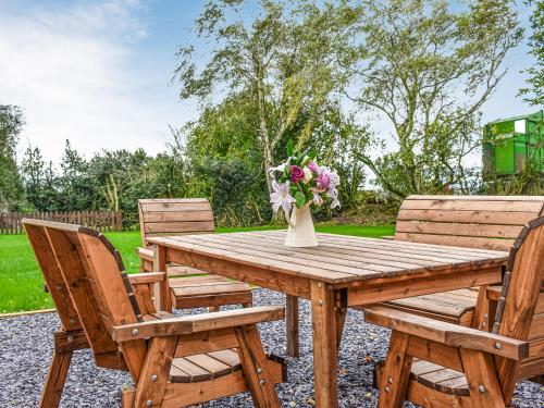 a wooden table with two chairs and a vase of flowers at Brynfields in Shirley