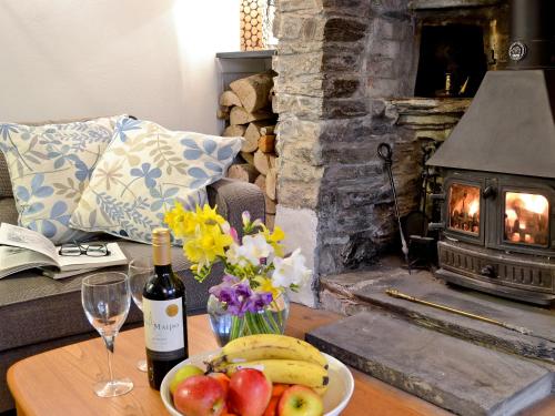 einen Tisch mit einem Obstteller und einer Flasche Wein in der Unterkunft The Thatch Cottage in South Petherwin