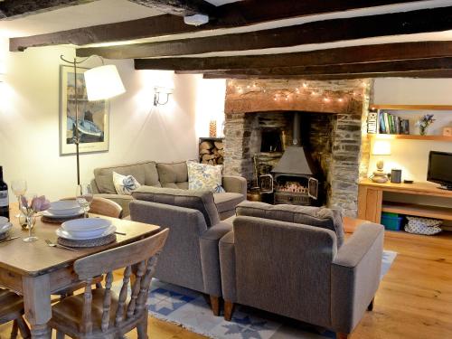 ein Wohnzimmer mit Couch und Kamin in der Unterkunft The Thatch Cottage in South Petherwin