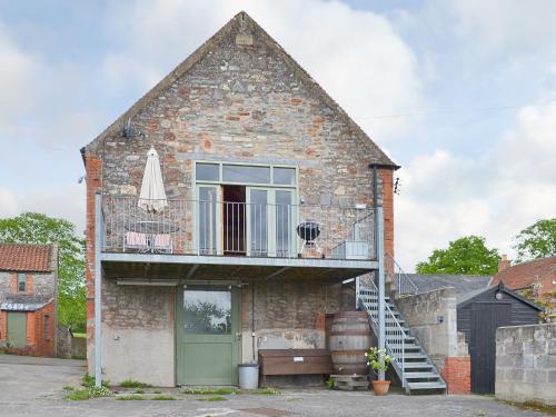 an old brick house with a balcony and an umbrella at Little Burcott Loft in Wookey
