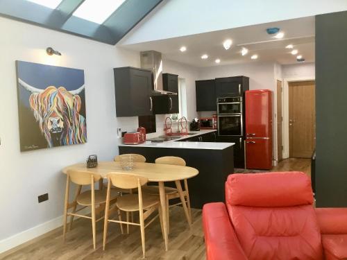 a kitchen with a small table and a red chair at Tidereach - Otters View in Connel