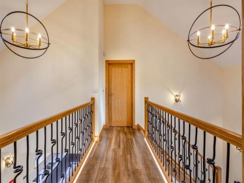 a hallway with two chandeliers and a wooden door at Garth House - Castlesteads in Brampton