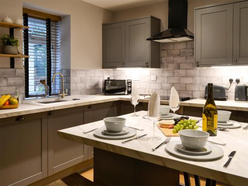 une cuisine avec une table avec des assiettes et des verres à vin dans l'établissement Terraughtie Cottage East-Uk31767, à Terreglestown