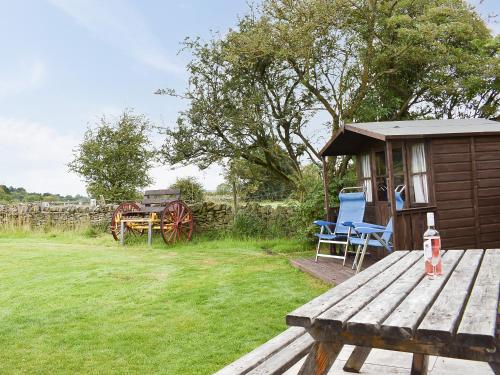 a small cabin with a picnic table and a bench at Skipton Shepherd's Hut - Dales View in Cononley