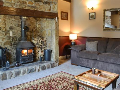 a living room with a stone fireplace and a couch at Quarryman's Cottage in Belford