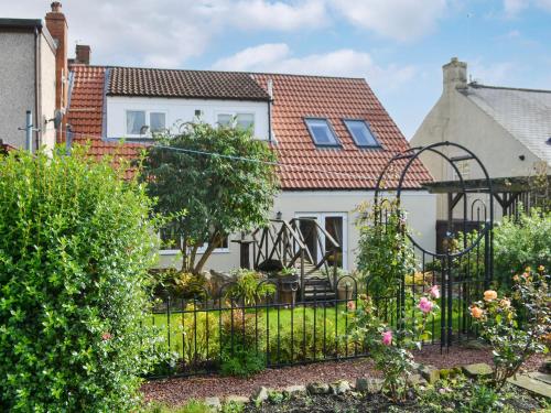 a garden with a black fence in front of a house at Quarryman's Cottage in Belford