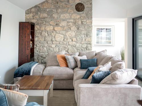 Una sala de estar con un sofá y una pared de piedra. en Stanton, en Bangor