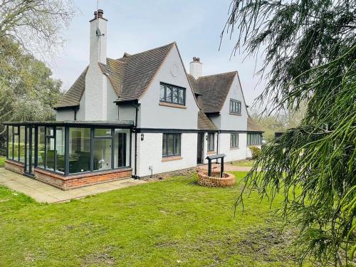 a large white house with glass doors on a yard at Warren Lodge in Little Baddow