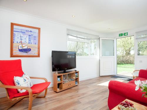 ein Wohnzimmer mit einem TV und roten Stühlen in der Unterkunft Lodge 133 - Uk43196 in Saint Merryn
