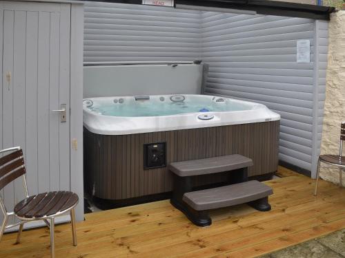 a bathroom with a tub and a chair and a stool at Kings House in Beaumaris