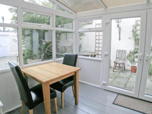 a dining room with a table and chairs and windows at Kings House in Beaumaris