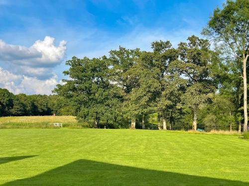 a large green field with trees in the background at The Lodge At The Lake House in Plaistow