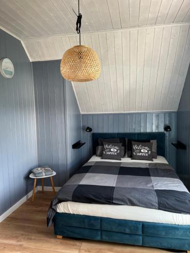 Un dormitorio con una cama con paredes azules y una lámpara de araña. en Turkusowy Domek, en Władysławowo