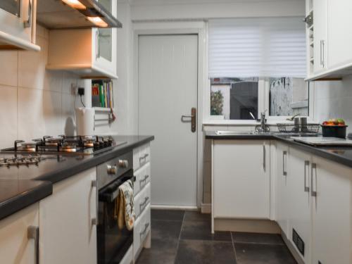 a kitchen with white cabinets and a stove at Coast To Coast Cottage in Cleator Moor