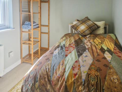 a bedroom with a bed with a quilt on it at Hysryb Cottage in Cardiff