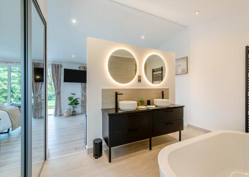 a bathroom with a black dresser and two mirrors at Faringdon Grange in Faringdon