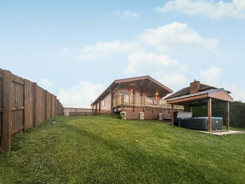 a large yard with a wooden house and a fence at Coo Lodge - Uk48430 in Falkirk