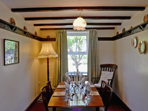a dining room with a table with chairs and a window at Murton Farm Cottage in Bishopston