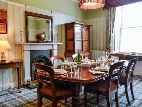 a dining room with a table and chairs and a fireplace at Craigvar House in Castle Douglas