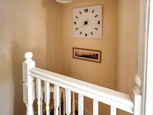 a white clock on a wall next to a staircase at Totland in Wootton Bridge