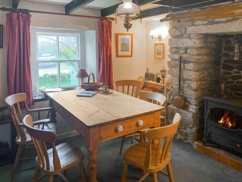 a dining room with a table and chairs and a fireplace at Pencaire in Helston