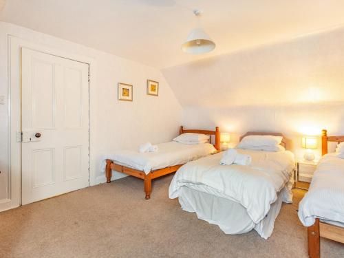two beds in a room with white walls at Isla Bank Cottage in Keith