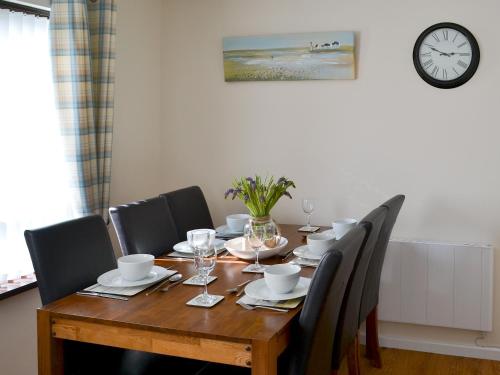 a dining room table with chairs and a clock on the wall at Villa 55 in Cromer