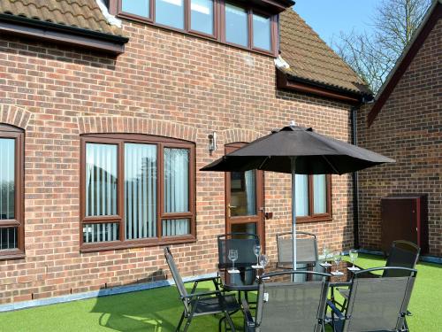a table with an umbrella in front of a brick building at Villa 55 in Cromer