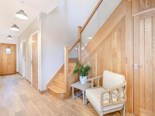 a hallway with a stairway with a chair and a plant at Hollyhocks - Uk47975 in Woodford