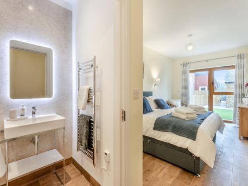 a bedroom with a bed and a sink and a mirror at Hollyhocks - Uk47975 in Woodford