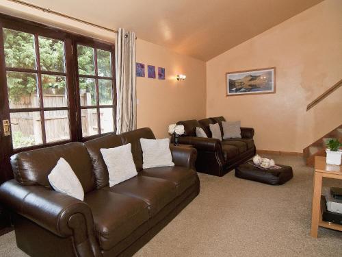 ein Wohnzimmer mit einem braunen Ledersofa und Stühlen in der Unterkunft St Andrews Barn in Necton
