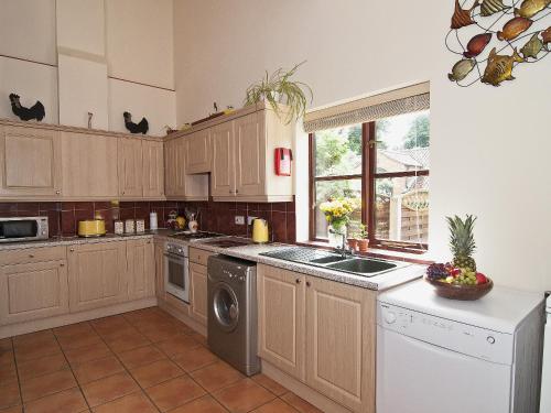 una cocina con fregadero y lavavajillas en St Andrews Barn, en Necton