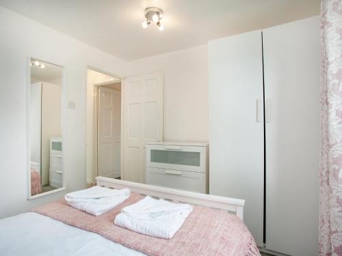 a bedroom with white walls and a bed with two towels at Number 13 in Gunnislake