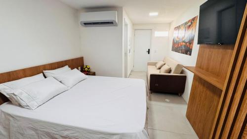 a bedroom with a white bed and a couch at Hoa Beach Flat 205 in Tamandaré