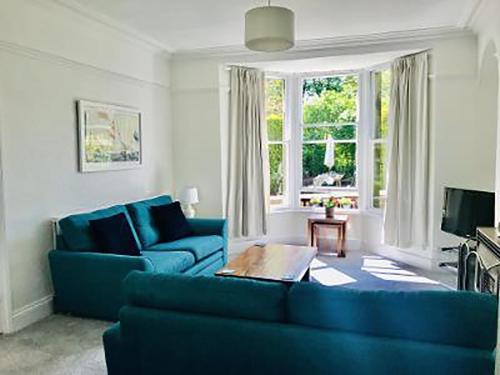 a living room with two blue couches in front of a window at Ivy Cottage in Skipton