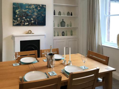 a dining room table with plates and glasses on it at Ivy Cottage in Skipton