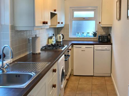 a kitchen with a sink and a stove top oven at Ivy Cottage in Skipton