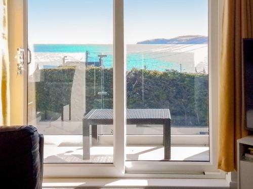 a window with a bench looking out at the ocean at Beach Cottage in Benllech
